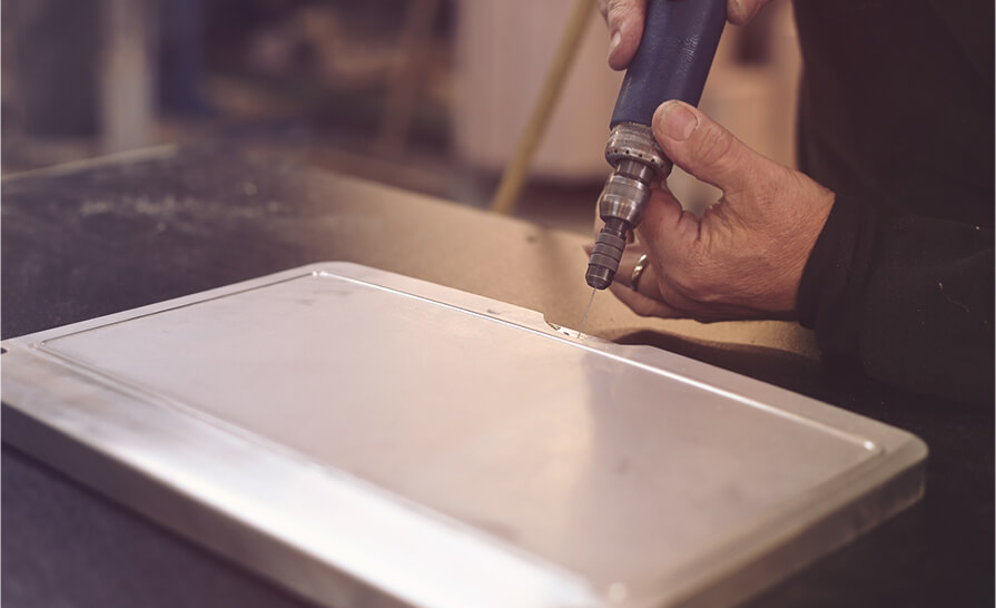 man drilling into a piece of metal