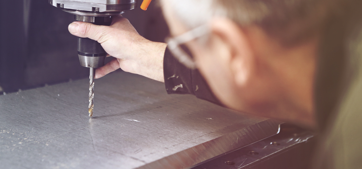 man drilling into a piece of metal